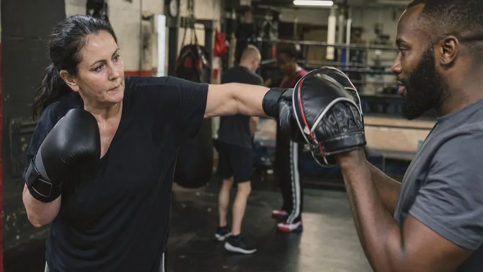 Care worker doing controlled padwork with a coach in a beginner boxing class