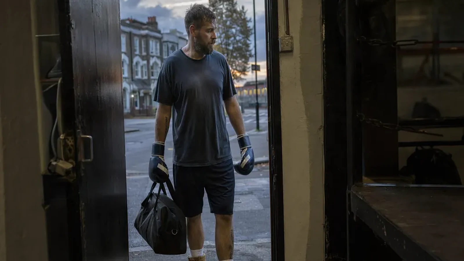 Adult boxer leaving a gym after training with gloves and a work bag
