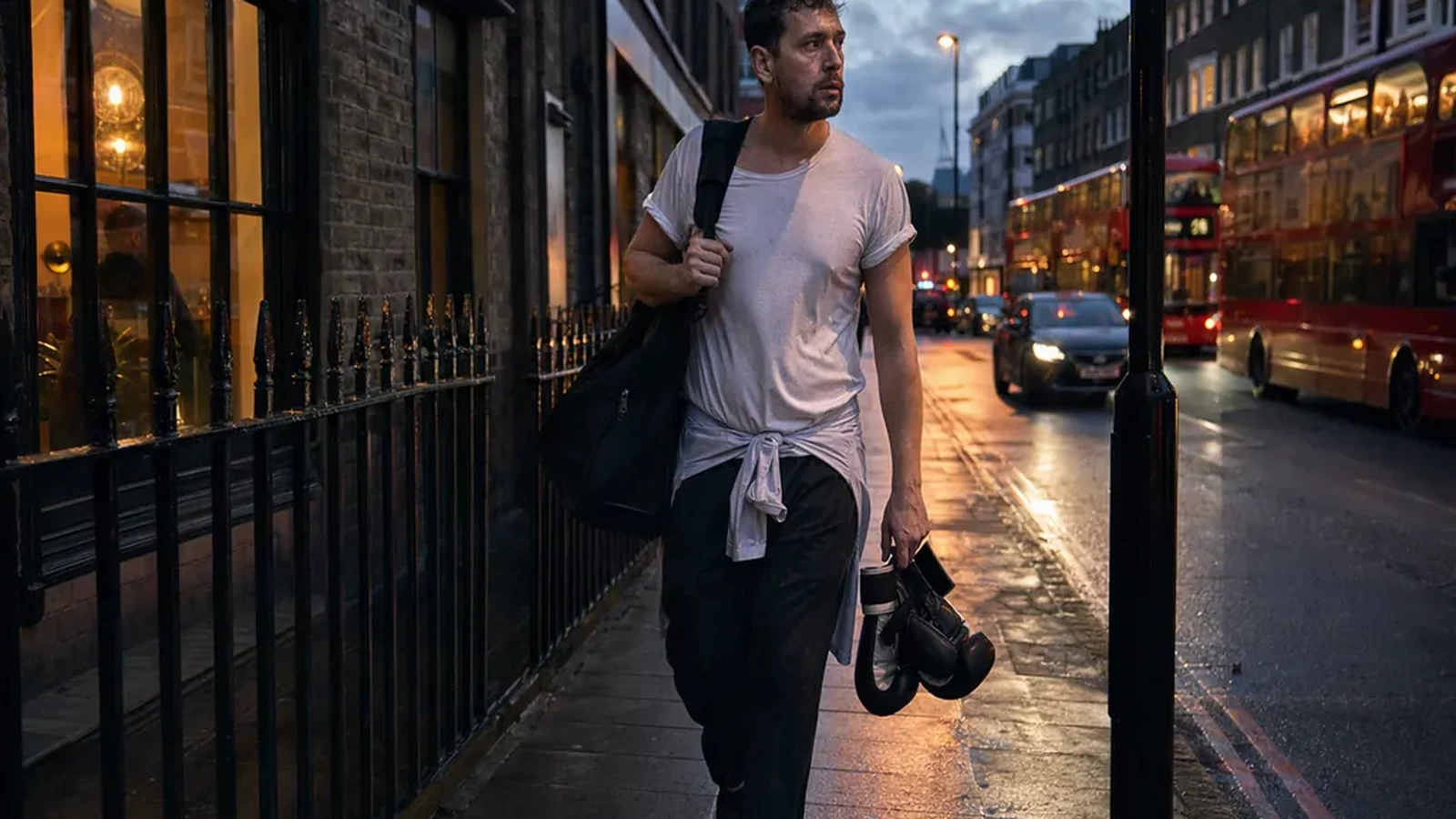 Chef walking home at dusk with boxing gloves and a gym bag after evening training