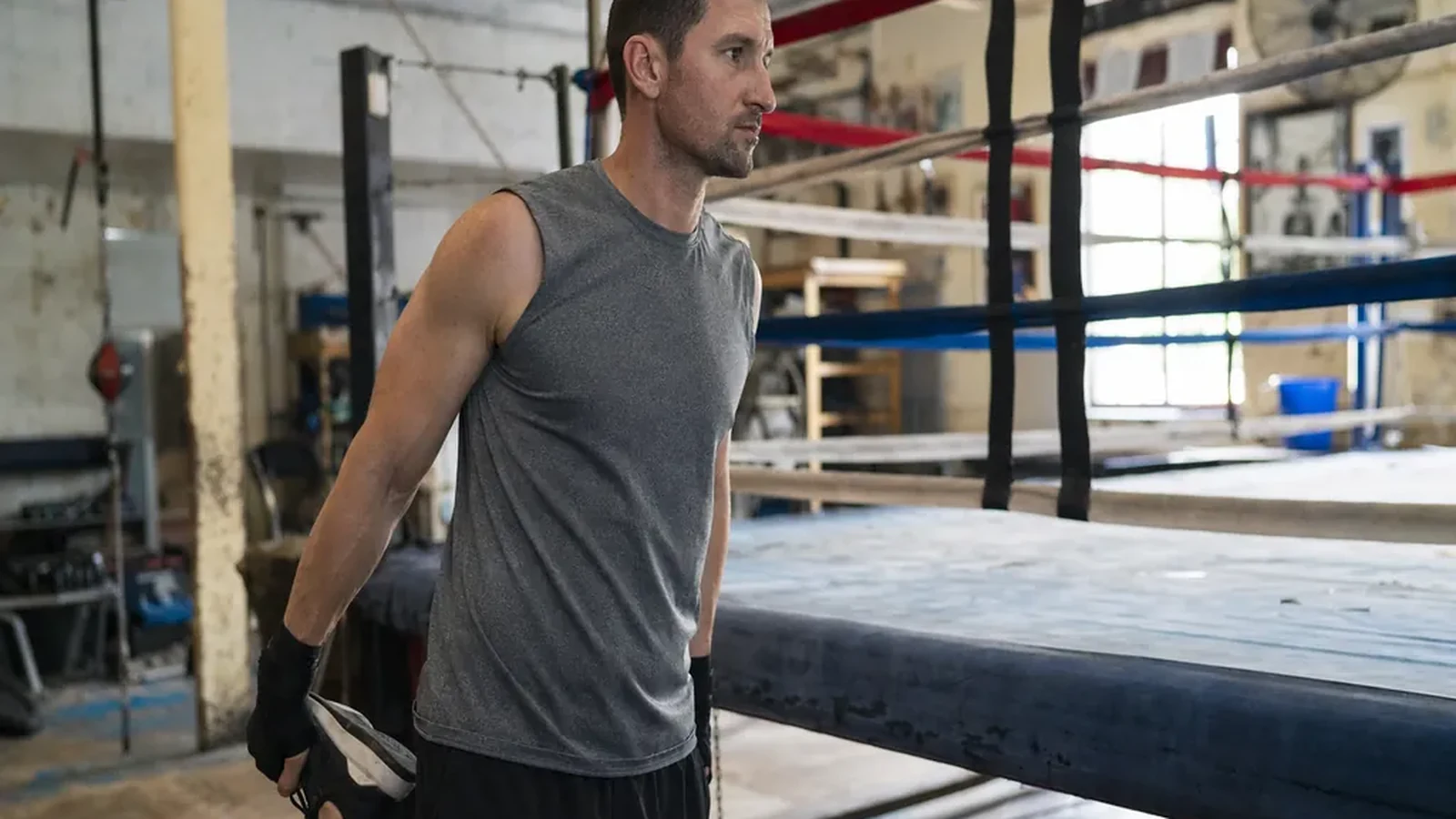 Adult beginner boxer stretching shoulders before training in a boxing gym