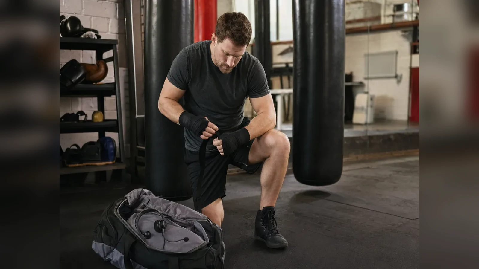 Adult beginner warming up beside heavy bags in a boxing gym