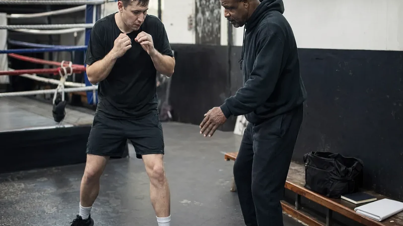 Adult beginner practising boxing footwork with a coach in a gym