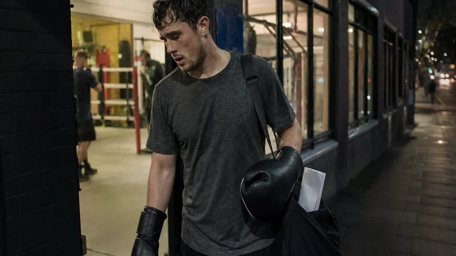 Adult boxer leaving a gym after training with gloves and a work bag