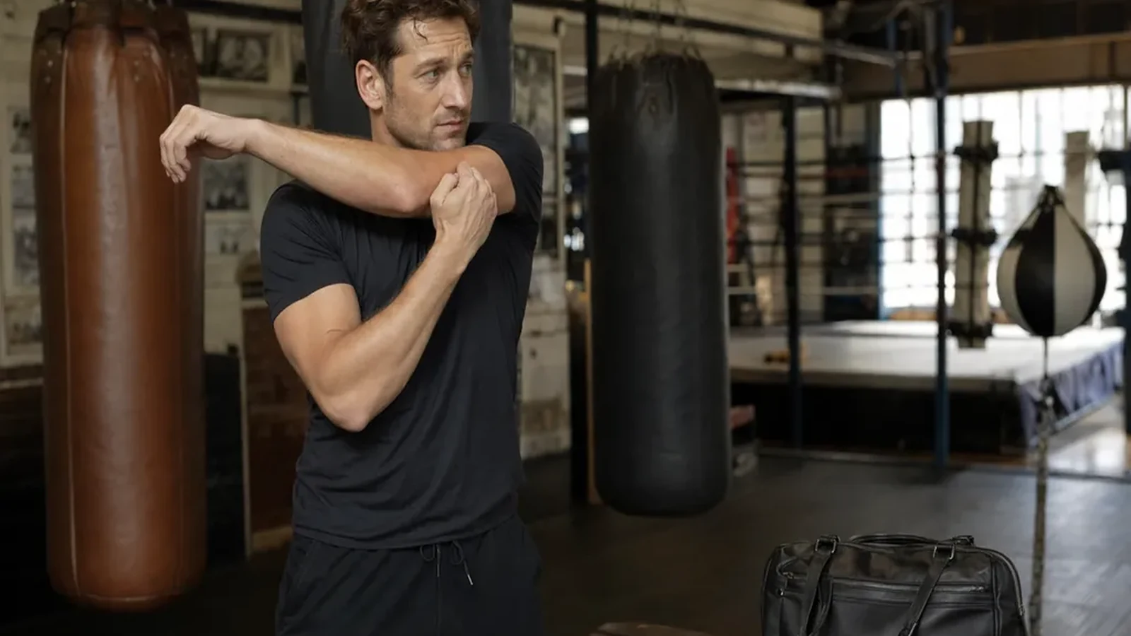 Estate agent in dark training kit warming up beside heavy bags after a day of viewings
