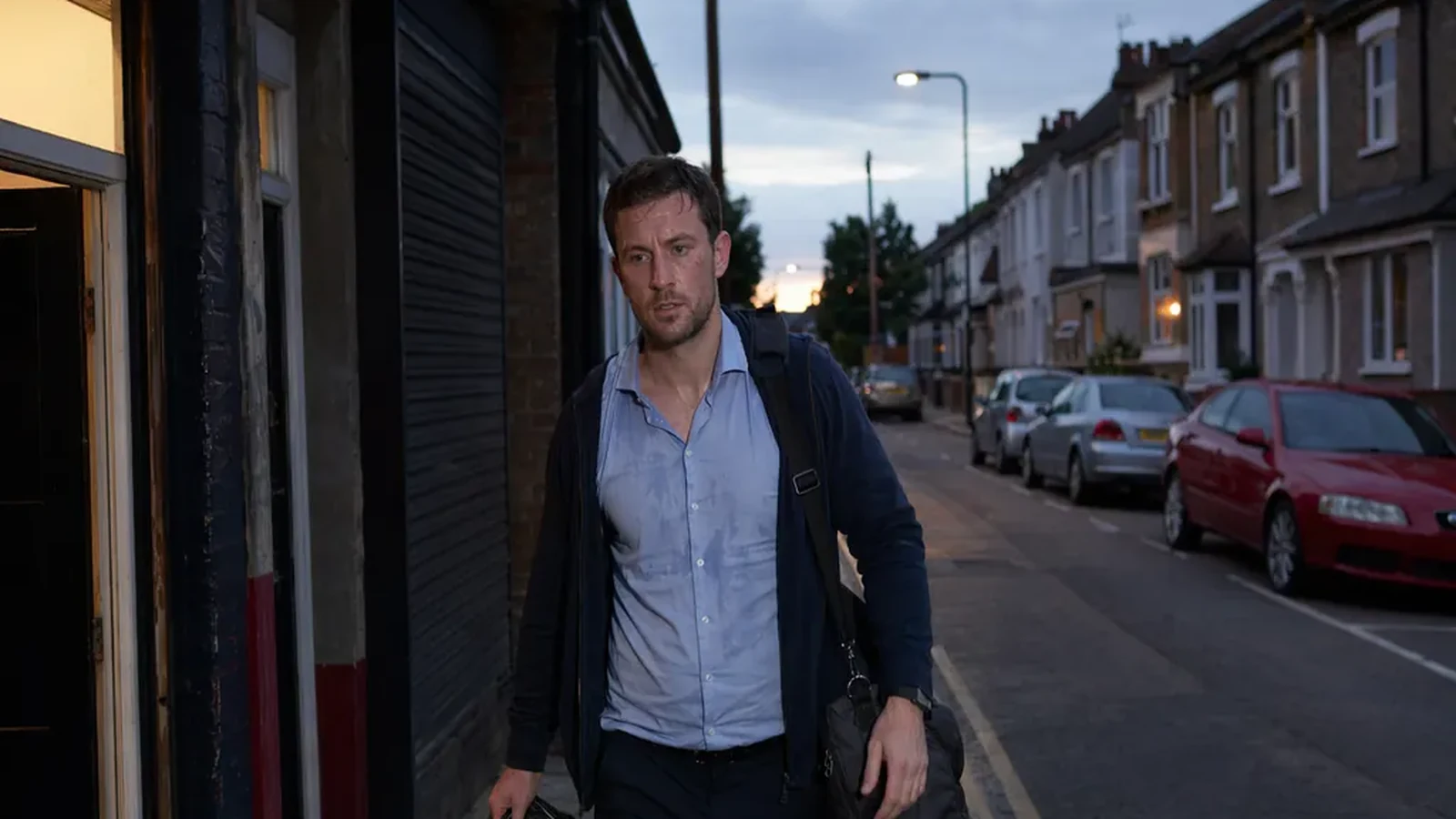 Estate agent leaving the boxing gym at dusk with gloves and a work bag after training