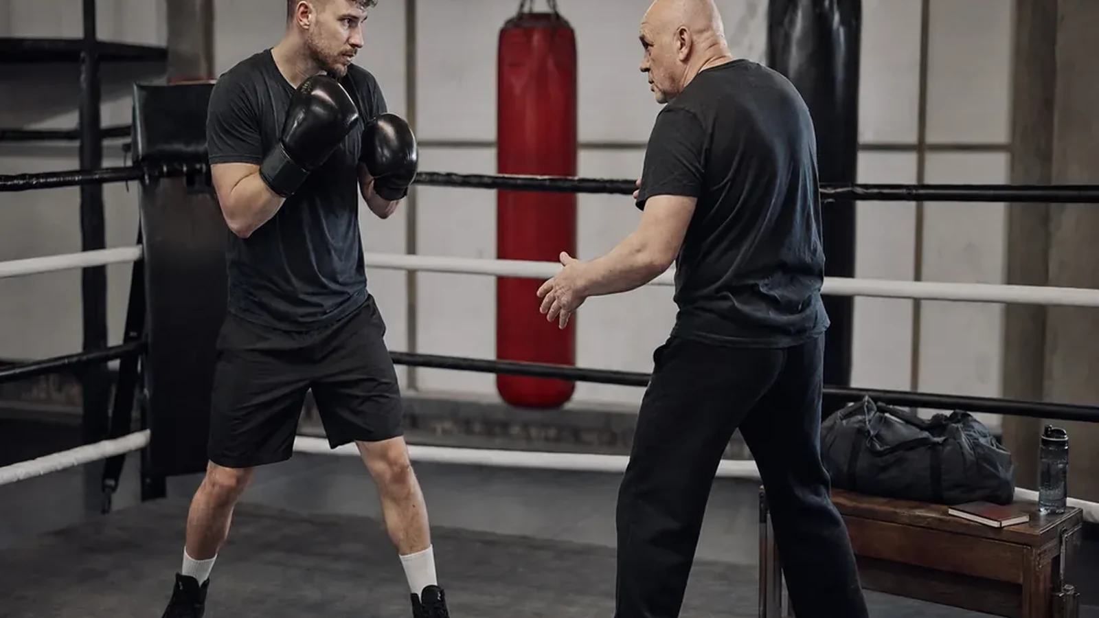 Adult beginner practising boxing footwork with a coach in a gym