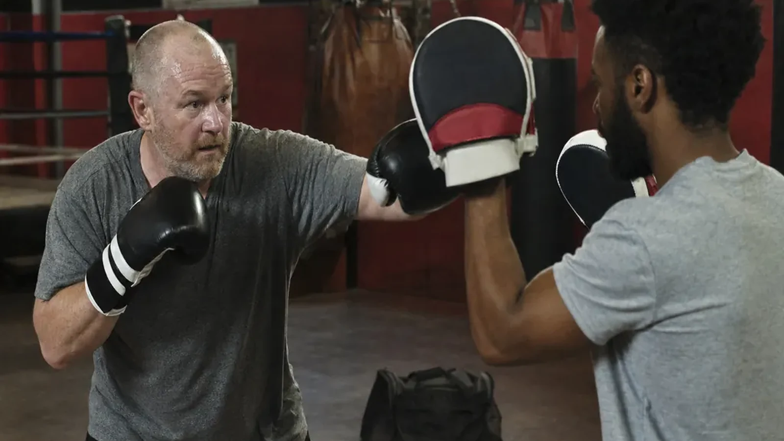 Adult beginner doing controlled boxing padwork with a coach