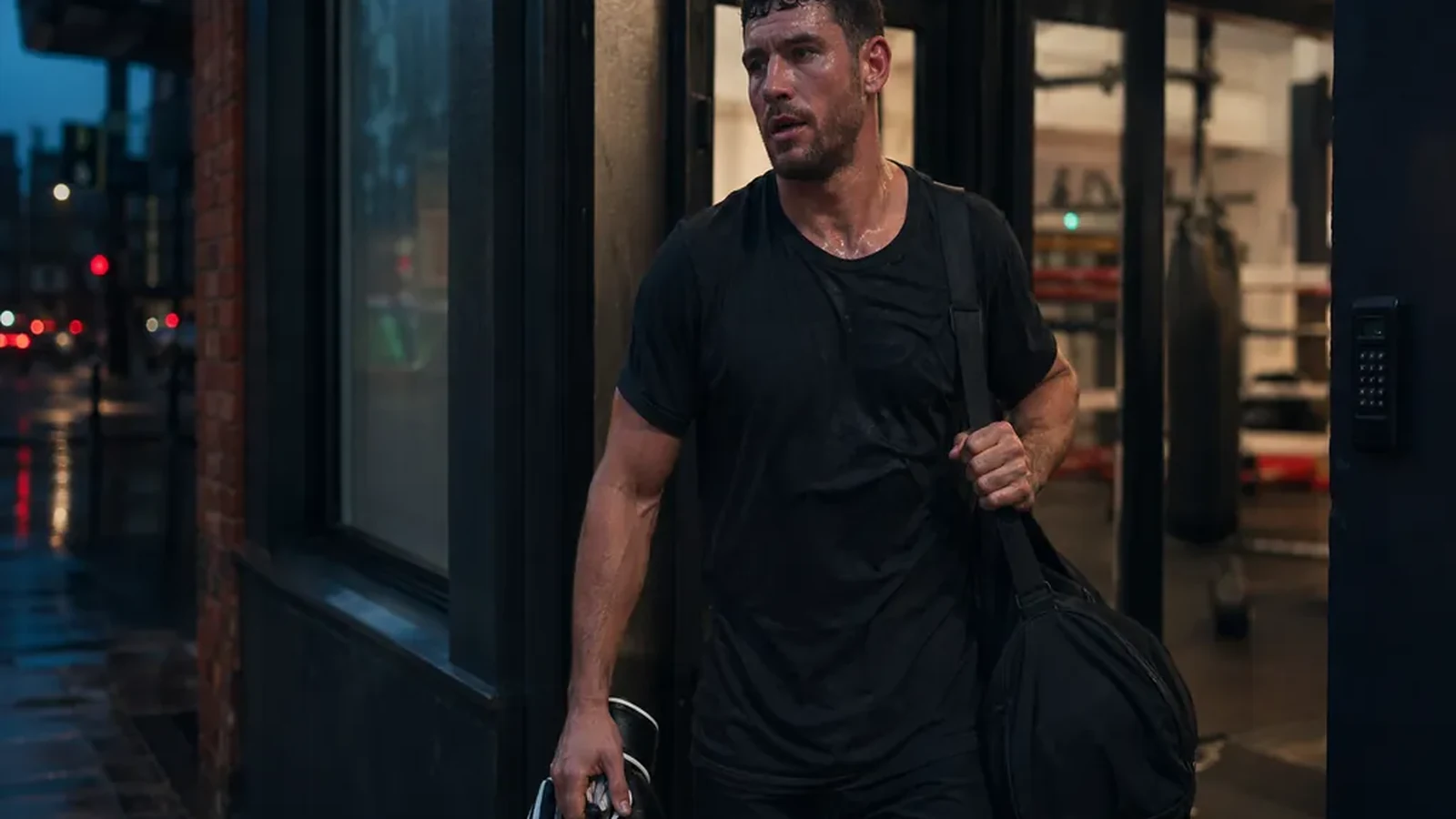 Adult boxer leaving a gym after training with gloves and a work bag