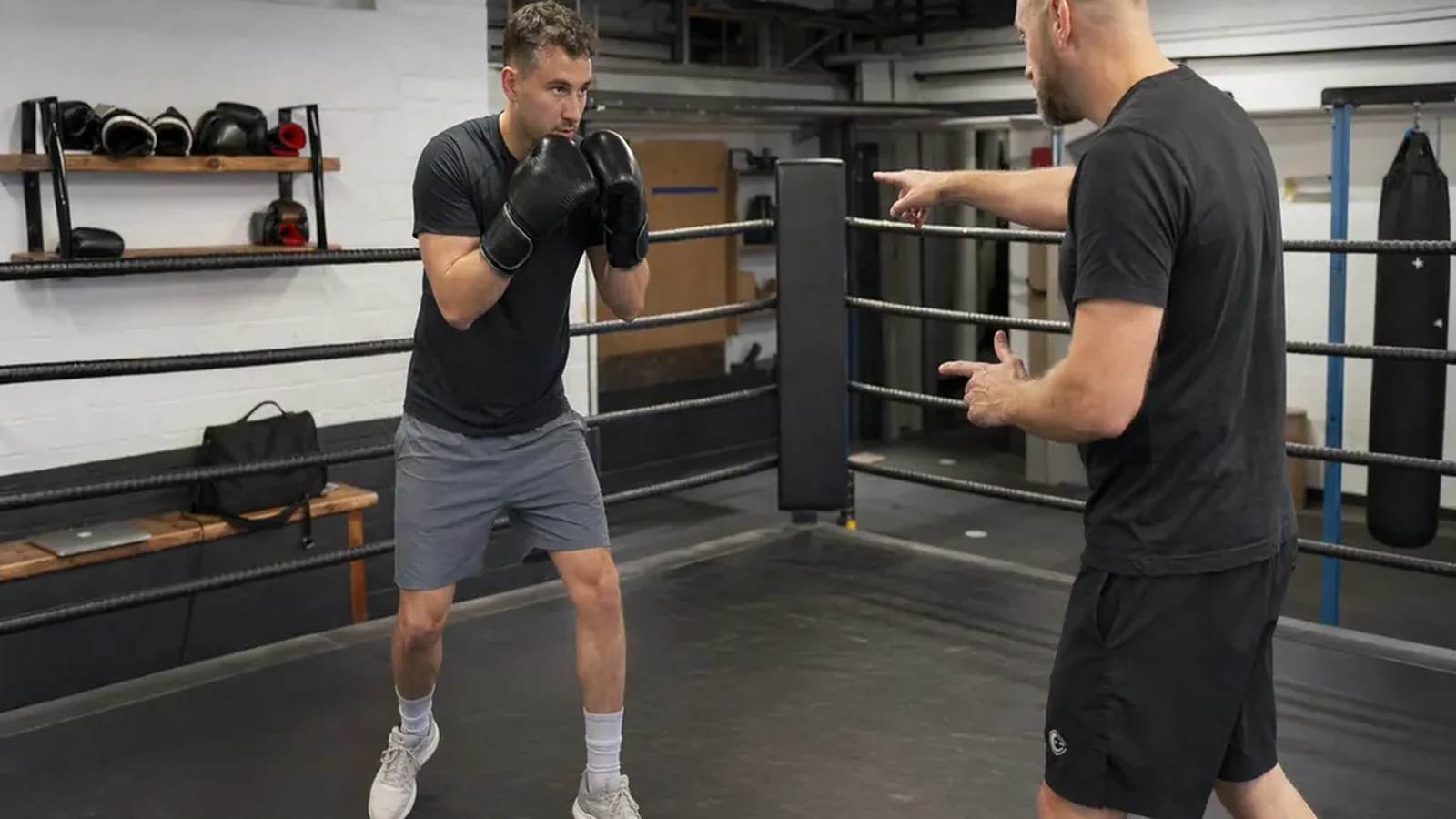 Adult beginner practising boxing footwork with a coach in a gym