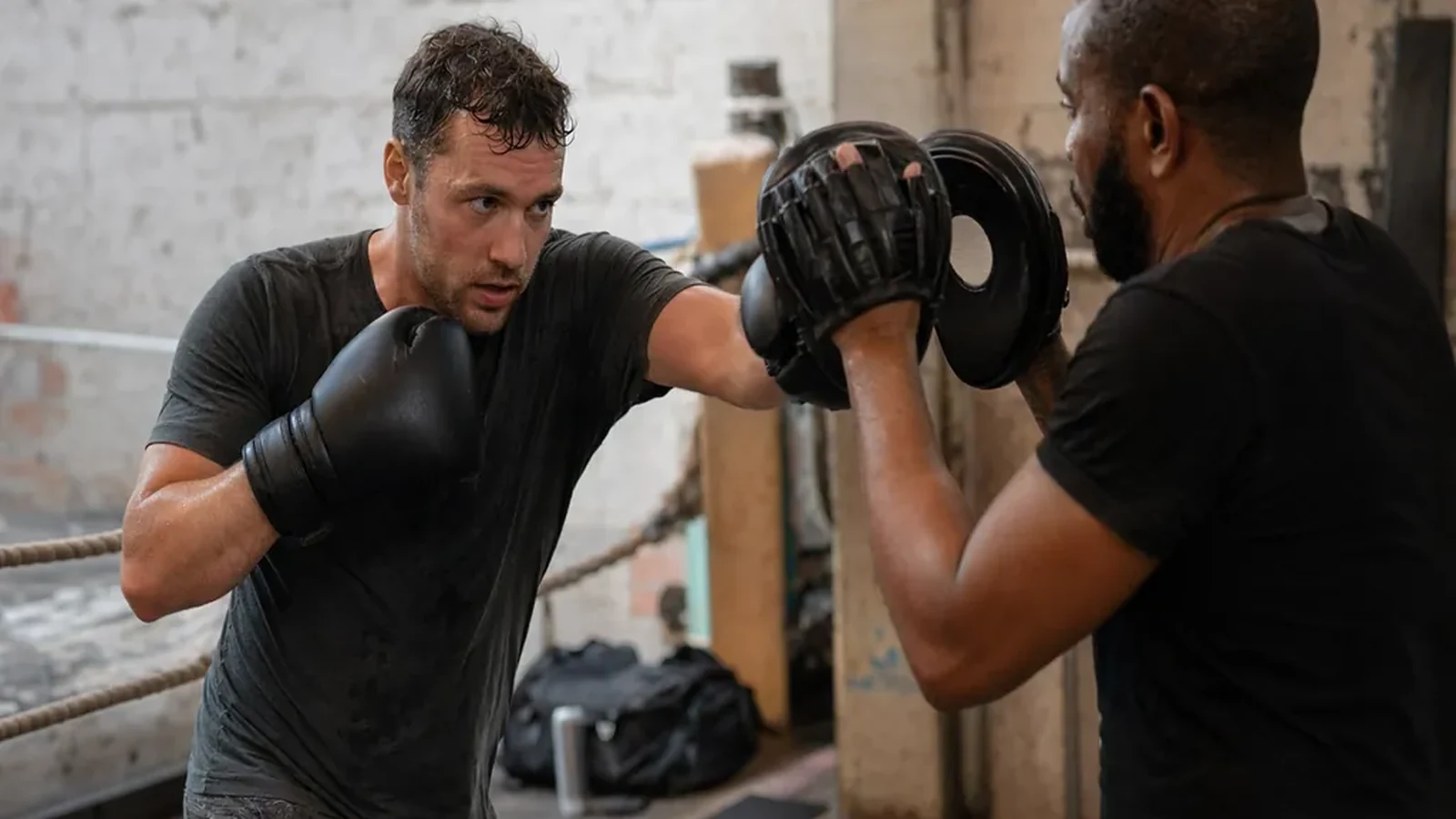 Adult beginner doing controlled boxing padwork with a coach