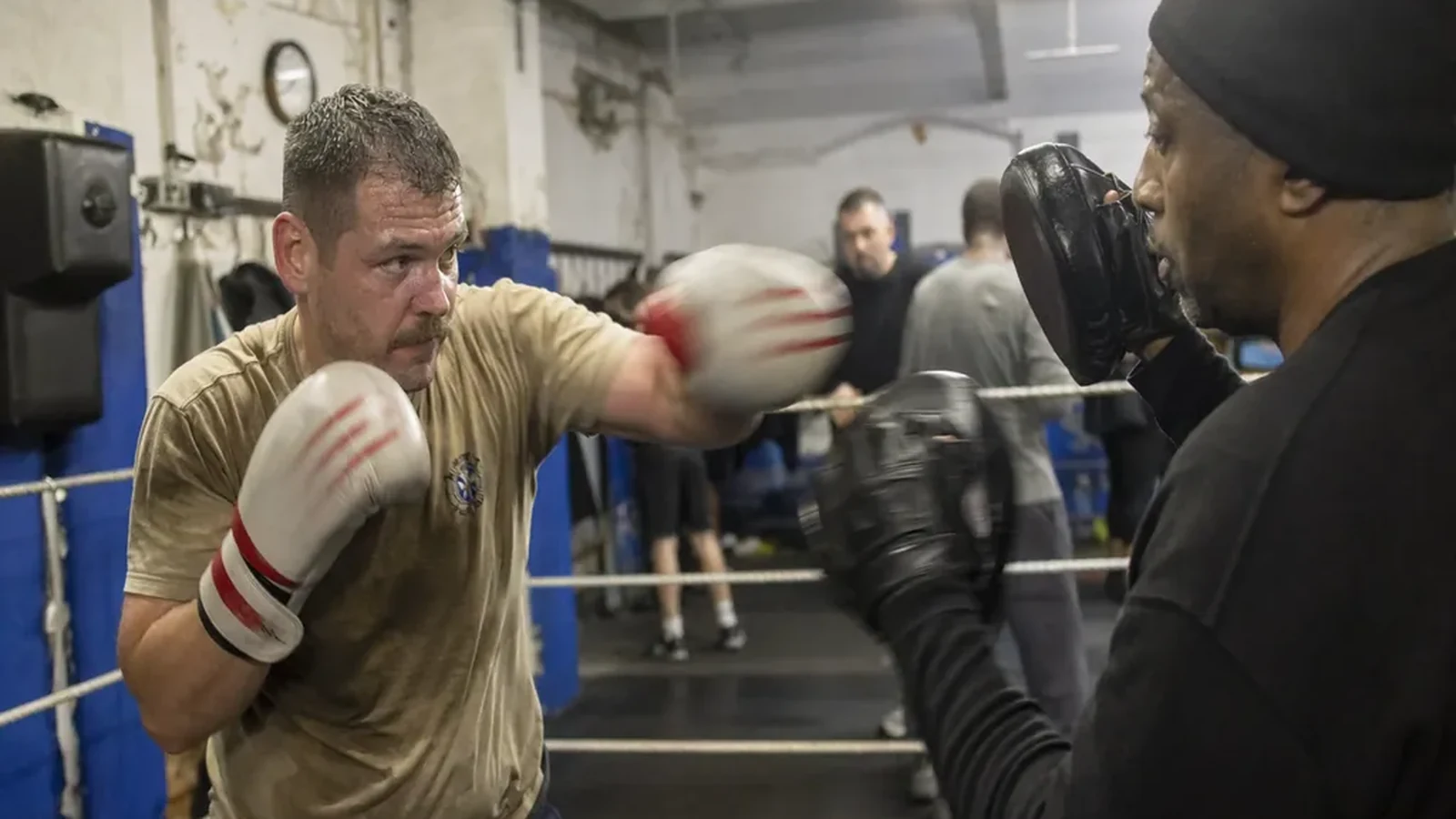 Firefighter or paramedic type adult working controlled pad combinations with a boxing coach in an evening class