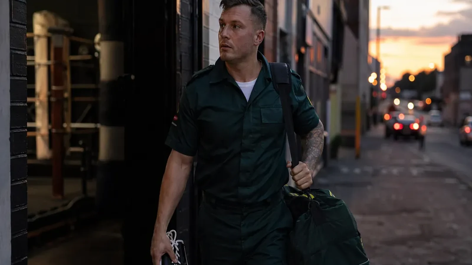 Emergency-service worker walking out of a boxing gym after training with gloves and a kit bag