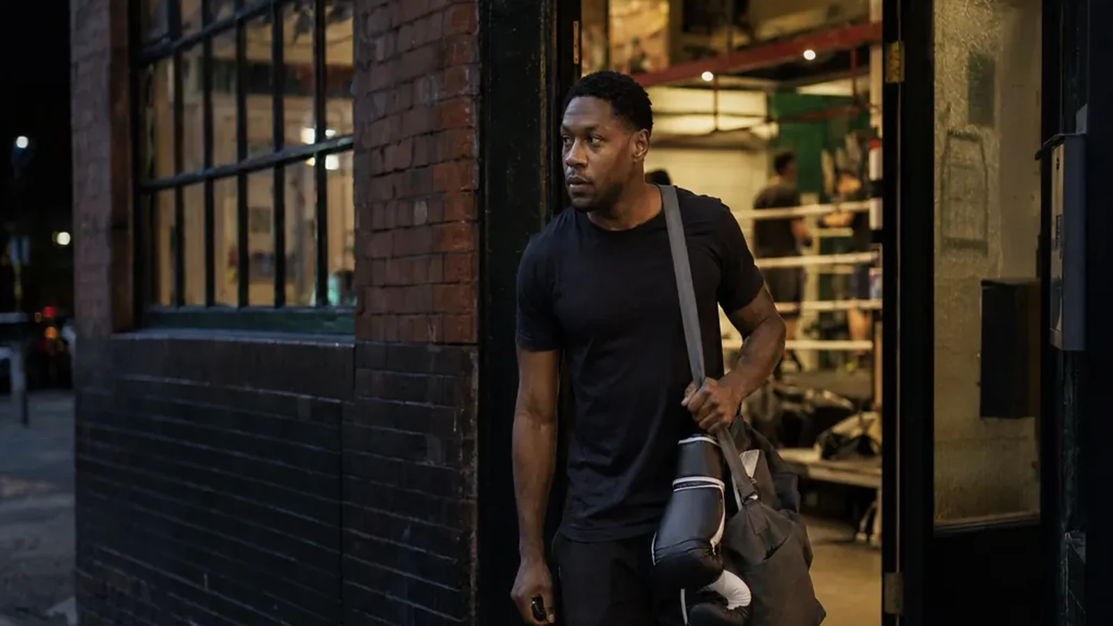 Adult boxer leaving a gym after training with gloves and a work bag