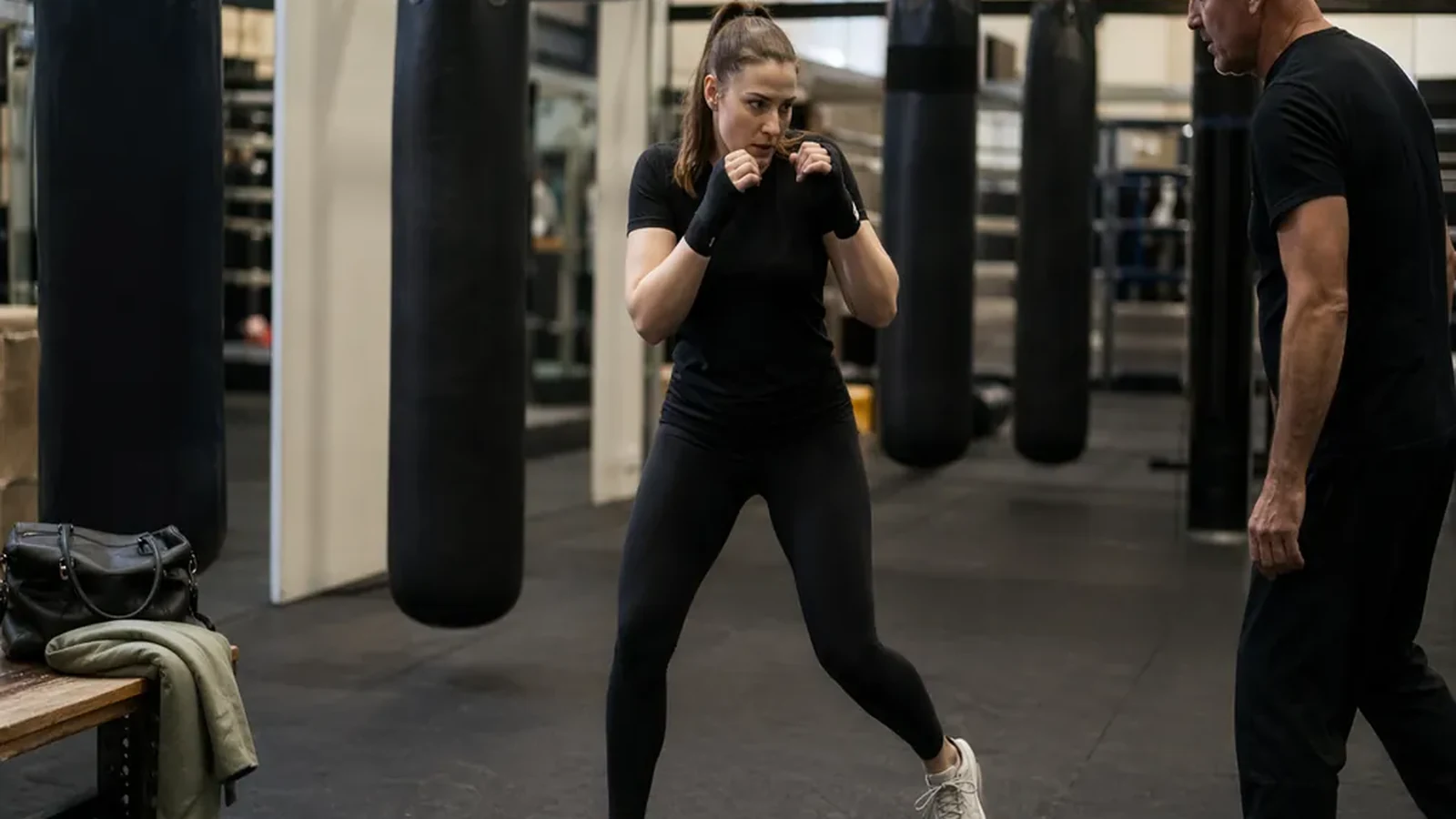 Adult beginner practising boxing footwork with a coach in a gym
