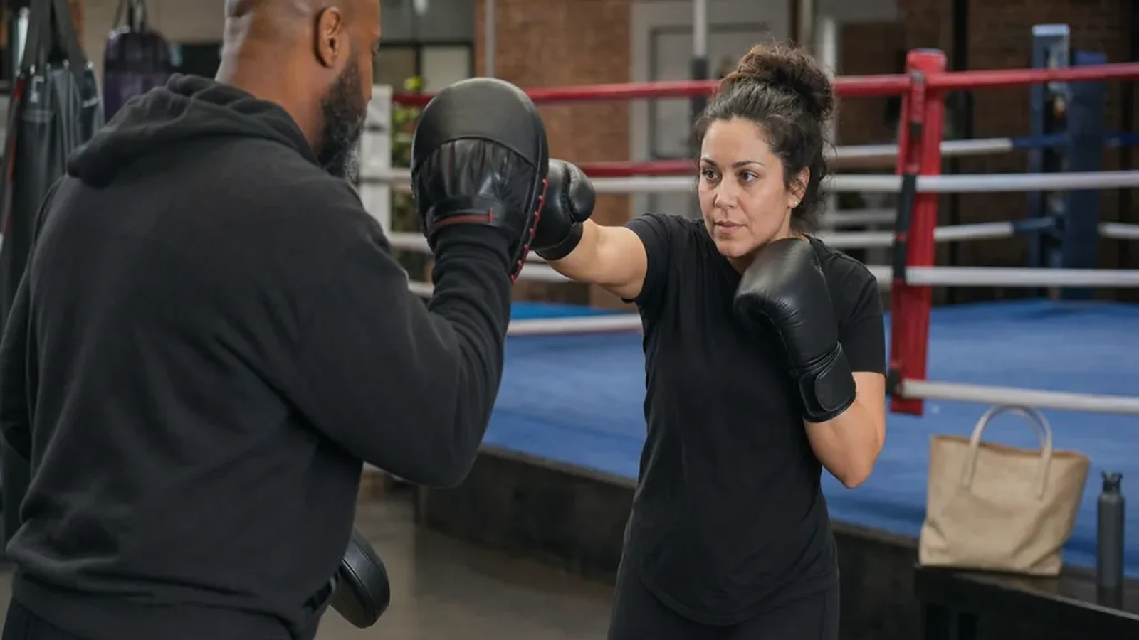 Adult beginner working controlled boxing pad combinations with a coach