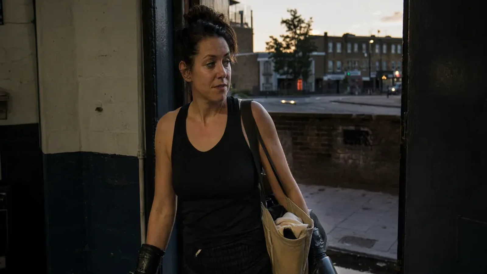 Adult boxer leaving a gym with gloves and a plain work bag