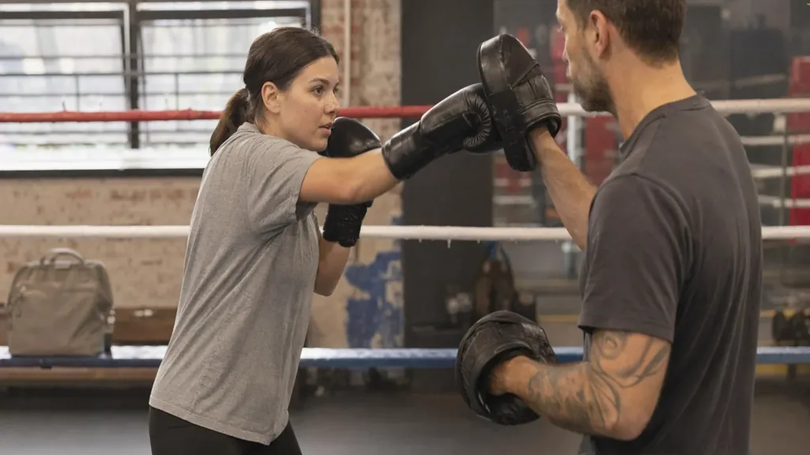 Hospitality worker doing controlled padwork with a boxing coach