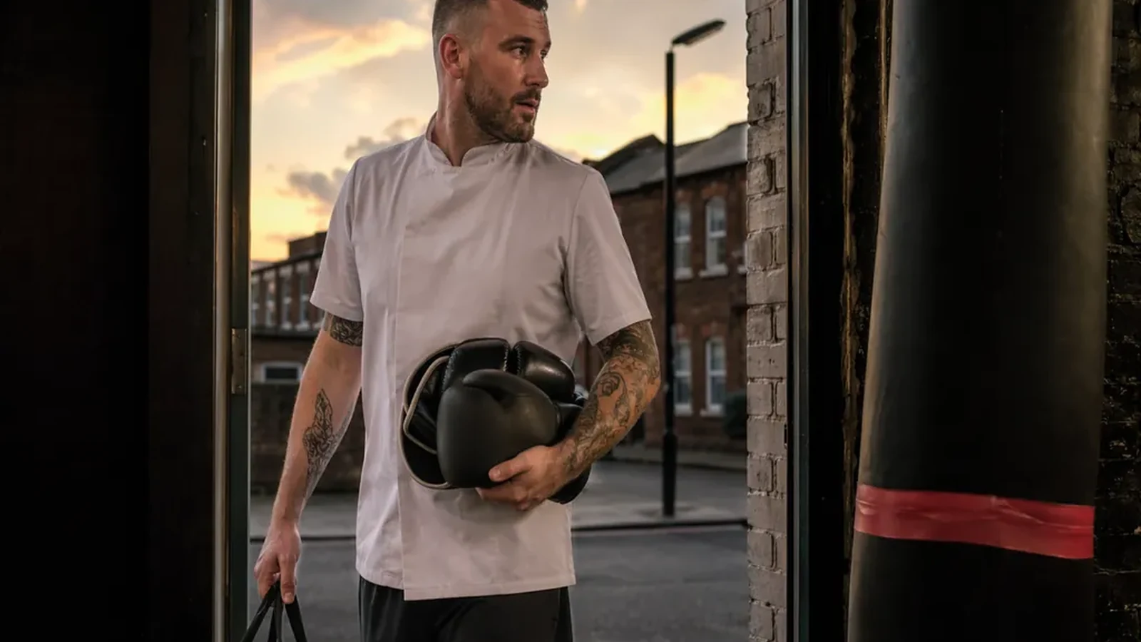 Hospitality worker leaving a boxing gym after training with gloves and a work bag