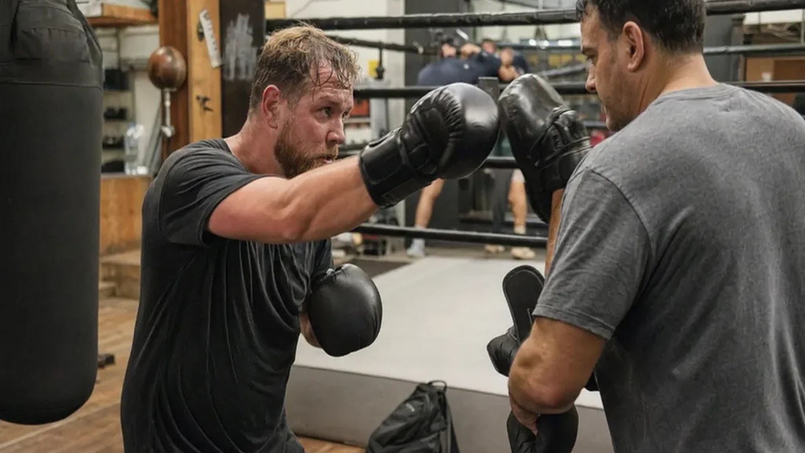 Adult beginner doing controlled boxing padwork with a coach