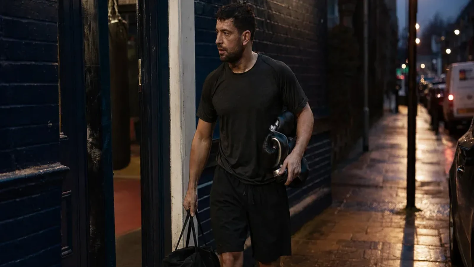 Adult boxer leaving a gym after training with gloves and a work bag