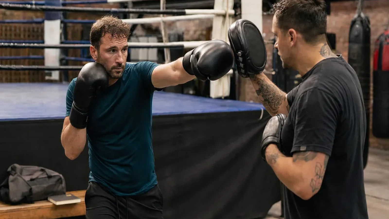 Adult beginner doing controlled boxing padwork with a coach
