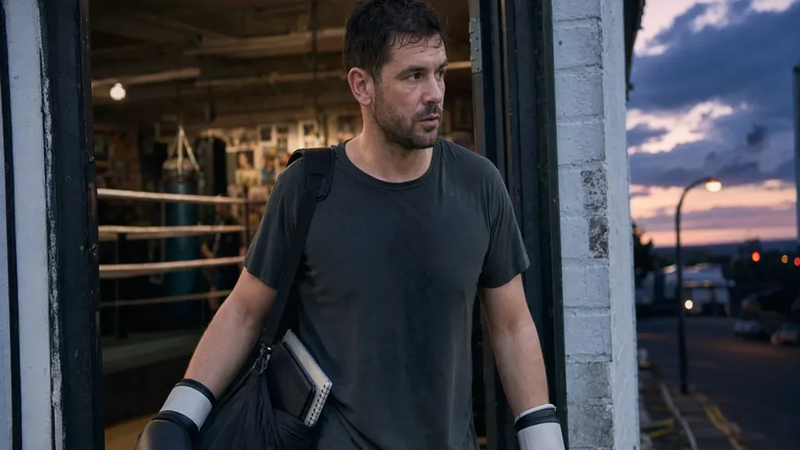 Adult boxer leaving a gym after training with gloves and a work bag