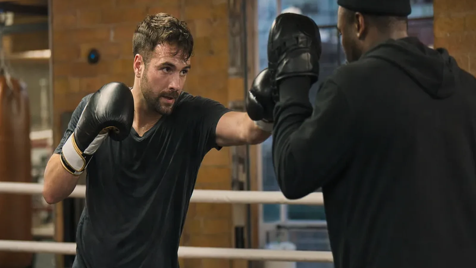 Man doing focused pad work with a coach during evening boxing training