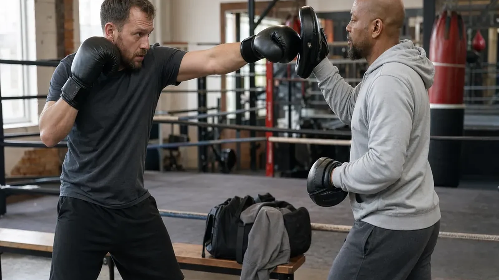 Adult beginner doing controlled padwork with a boxing coach