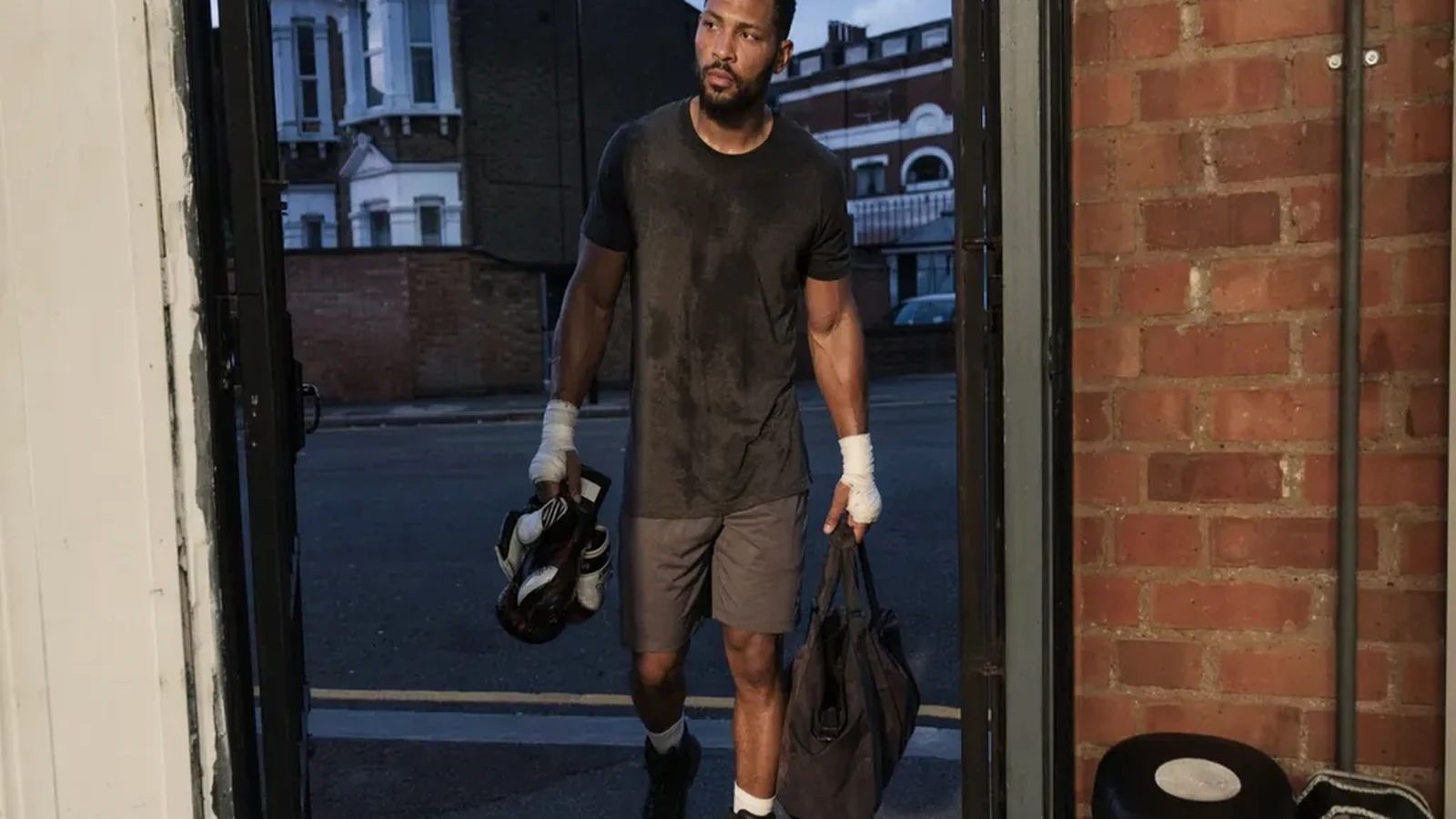 Adult boxer leaving a gym after training with gloves and a work bag