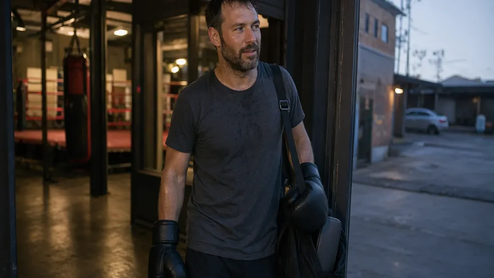Adult boxer leaving a gym after training with gloves and a work bag