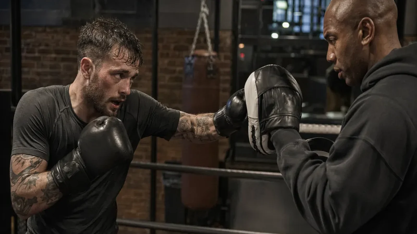 Man working pads with a coach during evening boxing training