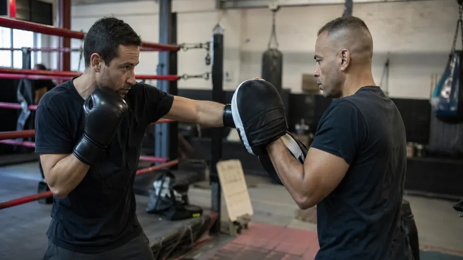 Adult beginner doing controlled boxing pad work with a coach