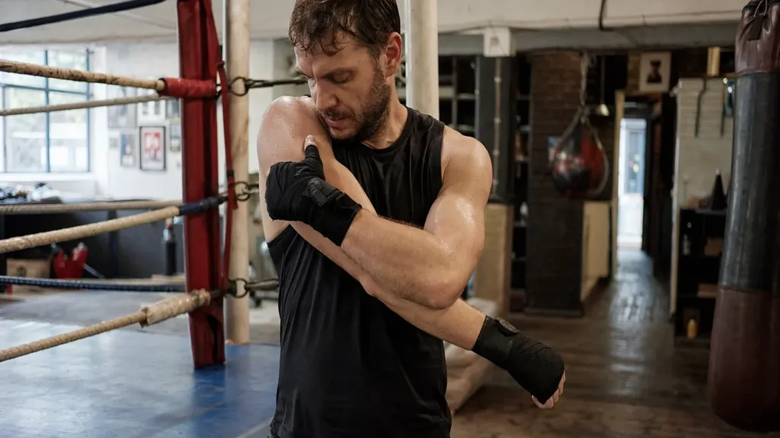 Beginner boxer holding his shoulder beside a boxing ring before training in a London gym