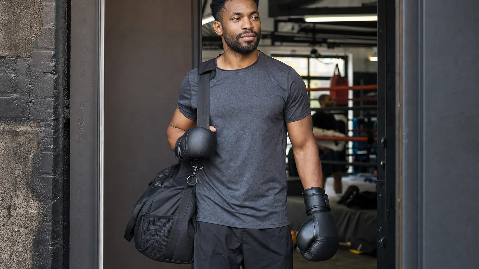 Adult boxer leaving a gym after training with gloves and a work bag