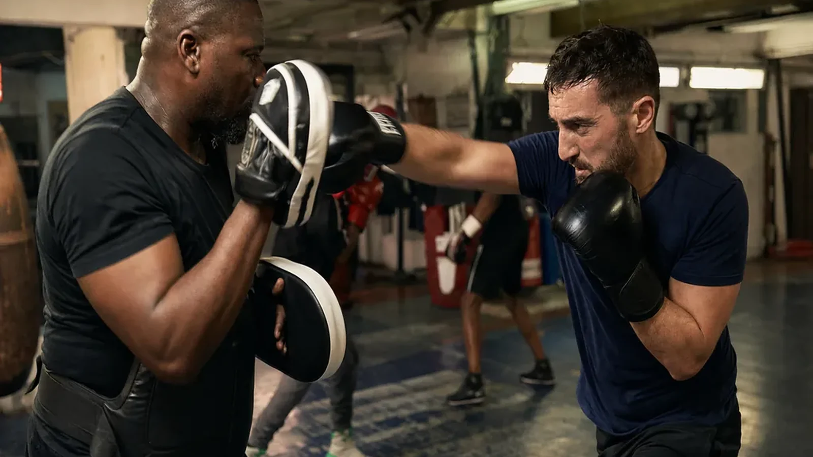 Salesperson working controlled pad combinations with a boxing coach