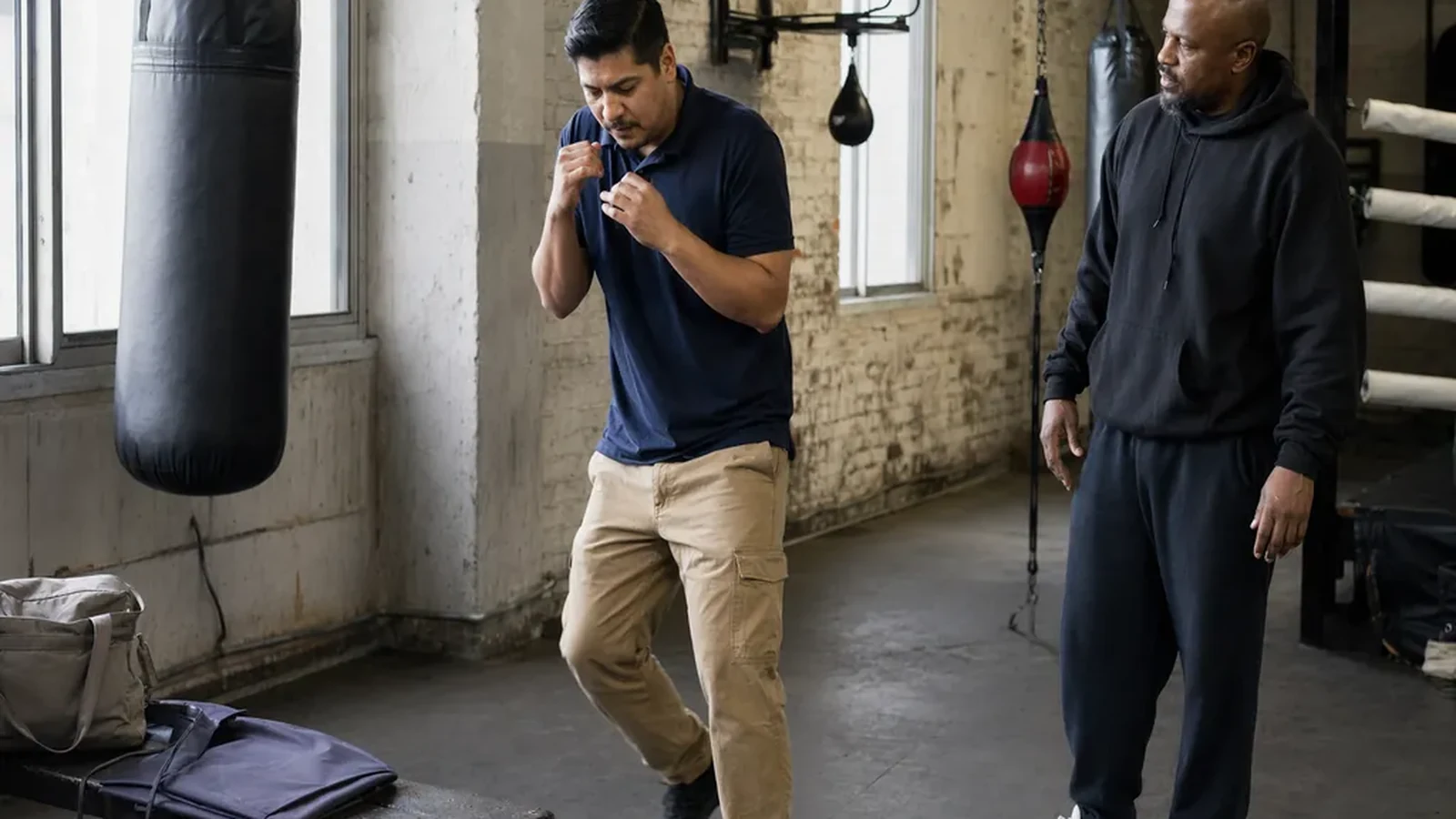 Adult beginner practising boxing footwork with a coach in a gym