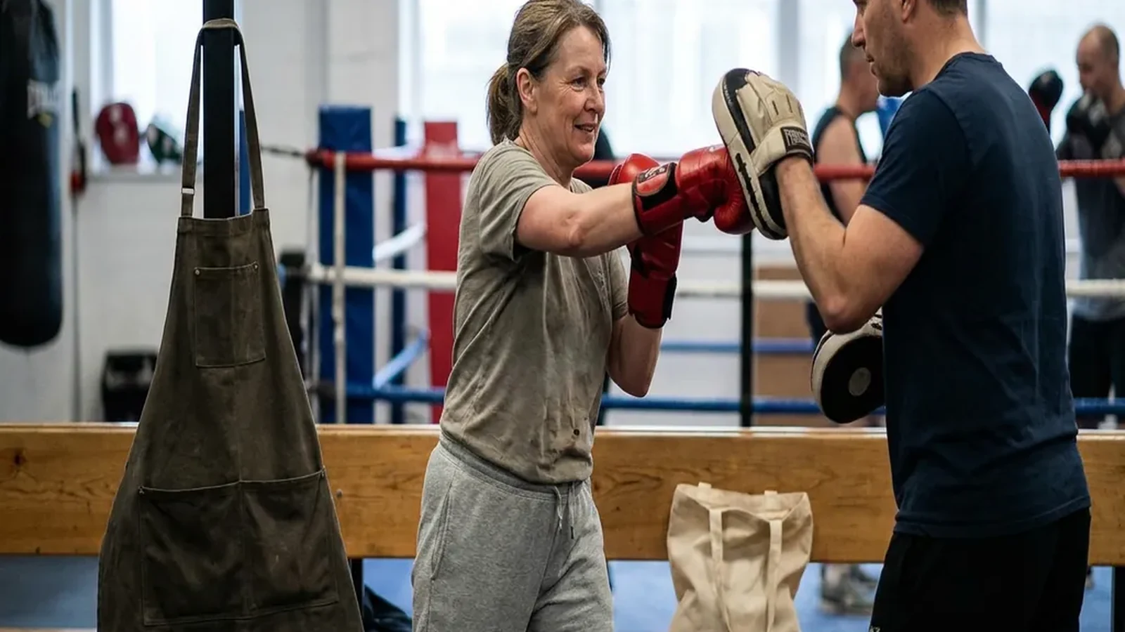 Adult beginner doing controlled padwork with a boxing coach
