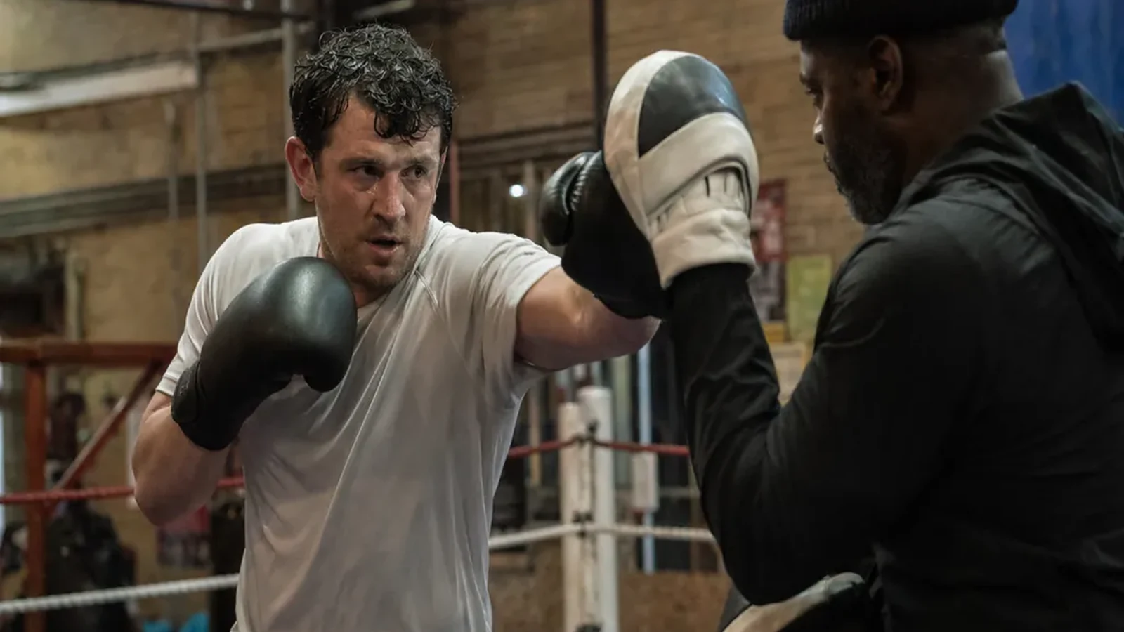 Man working pads with a coach during evening boxing training