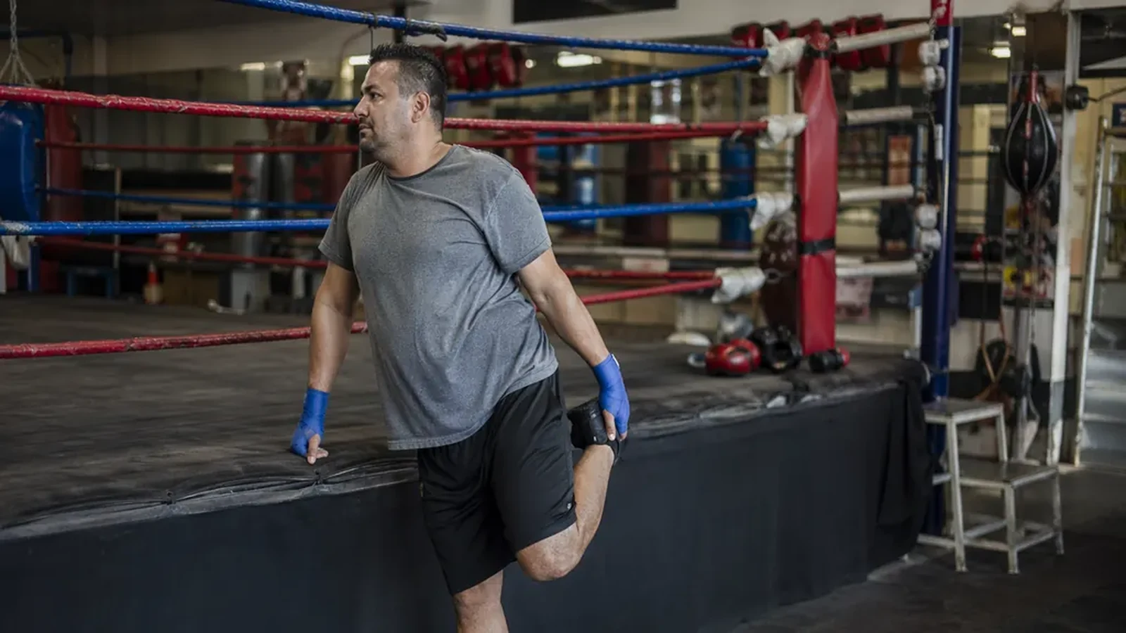 Adult beginner boxer stretching shoulders before training in a boxing gym