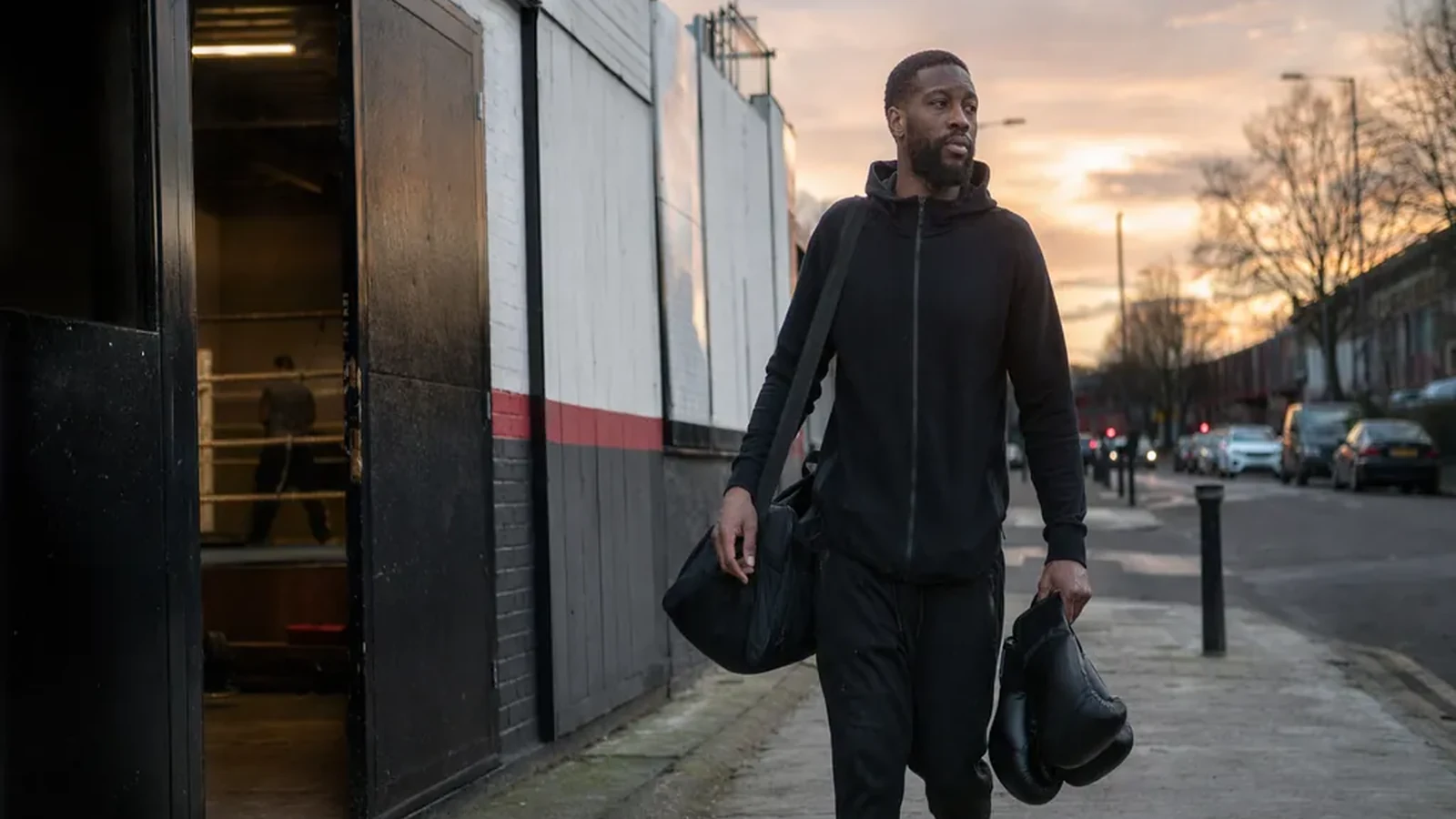 Warehouse worker leaving a boxing gym with gloves and a kit bag after training