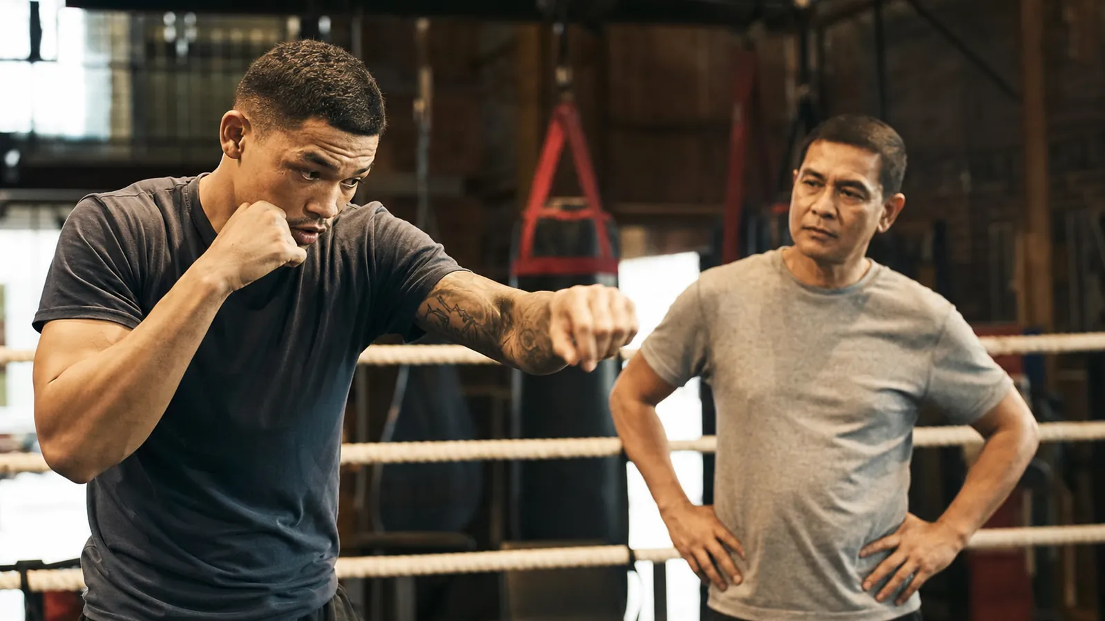 Boxer doing light non-contact shadowboxing while a coach watches return-to-training movement