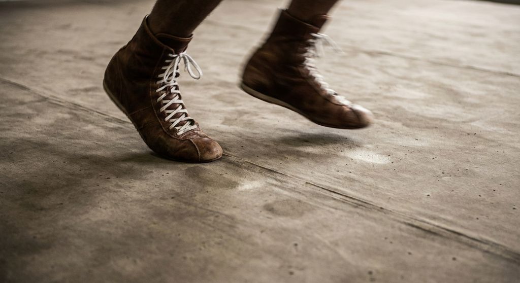 Close-up of boxer's feet doing precise footwork drill on the canvas. Movement fo
