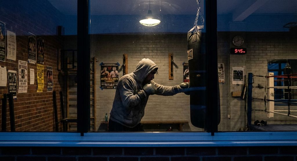 Consistent boxer training in empty gym late evening - dedication and habit