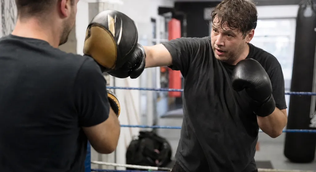 Adult beginner wrapping hands before an evening boxing class with a work bag nearby