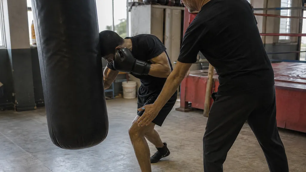 Adult recreational boxers drilling safe body-shot entries and a small pivot-out under coach supervision