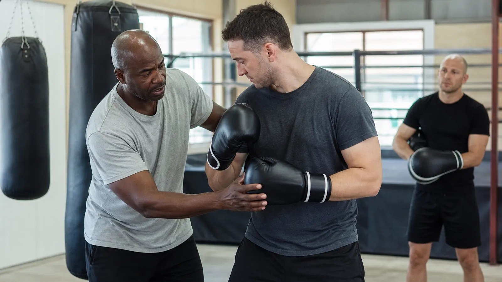 Boxing coach correcting an adult beginner's guard and stance during padwork