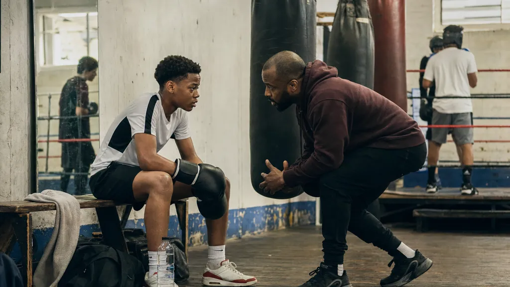 GCSE-age boxer taking a coached breather after bag work