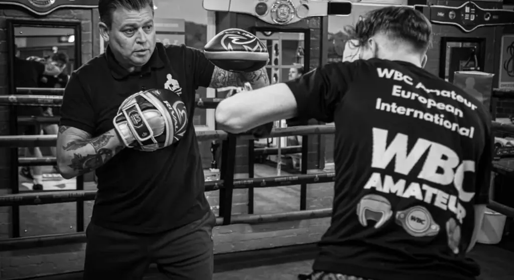 Coach holding pads during a focused boxing session at Honour and Glory