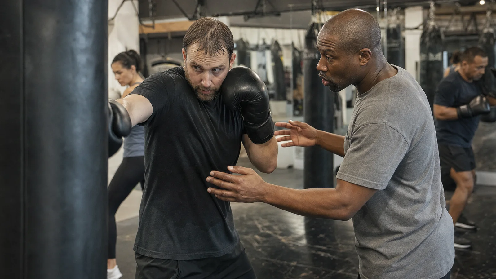 Adult boxer working pads with a coach giving a precise technical correction in a modest boxing gym