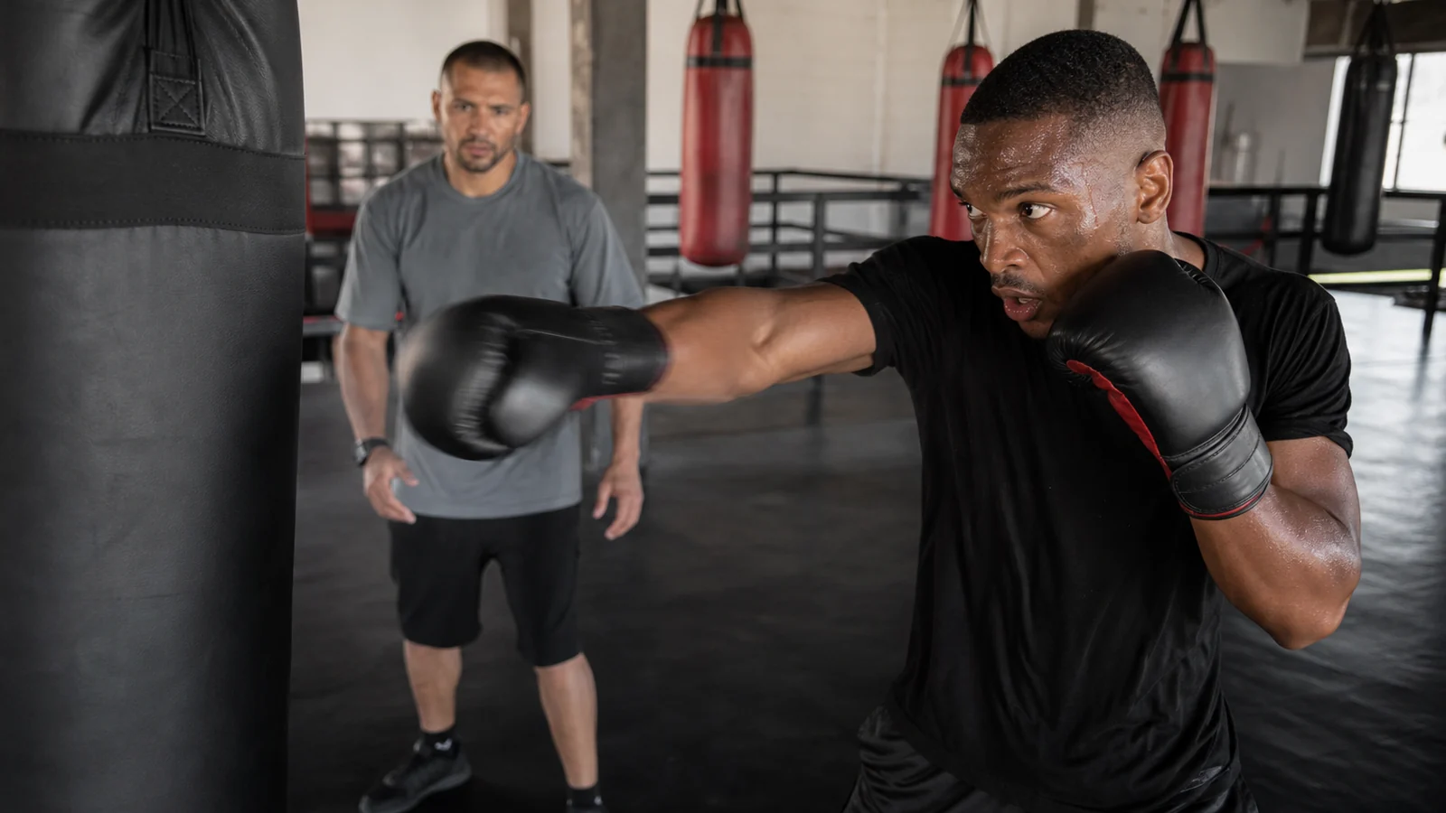Coach and adult beginner boxer practising punch-number calls on focus mitts